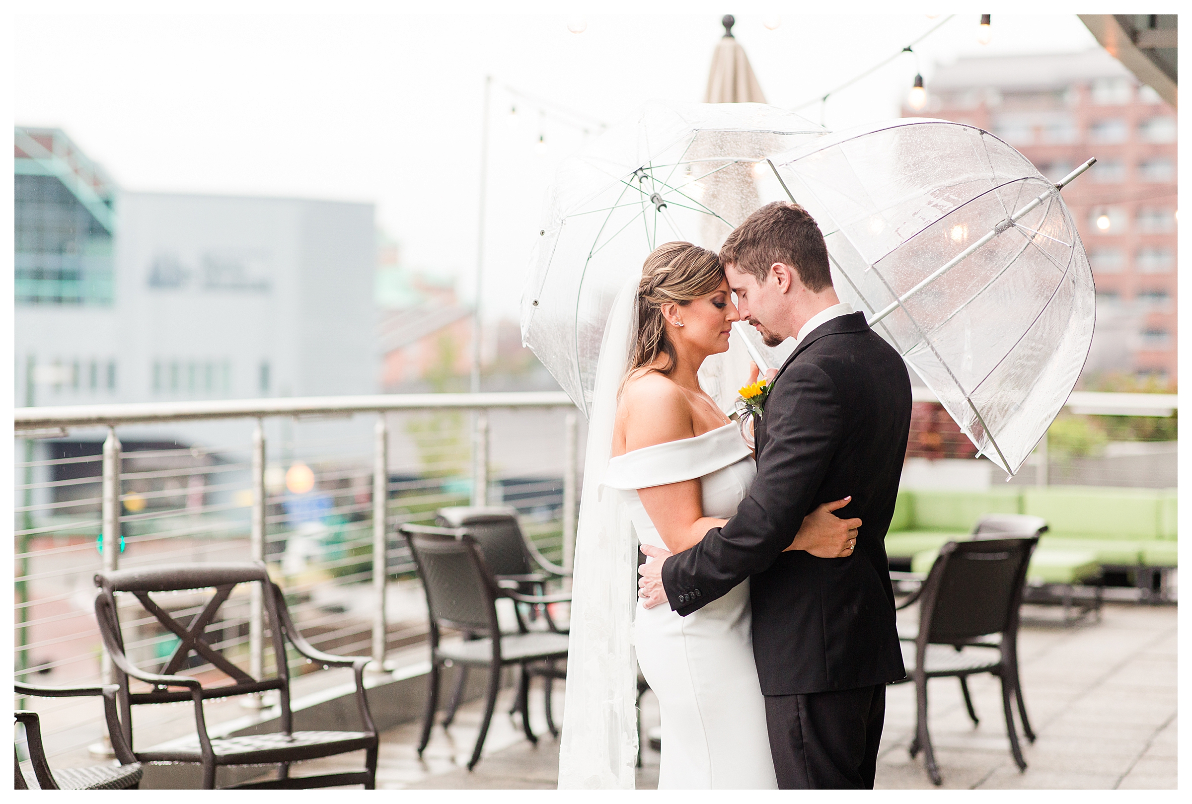 Bride & Groom embracing under umbrellas on wedding day.
