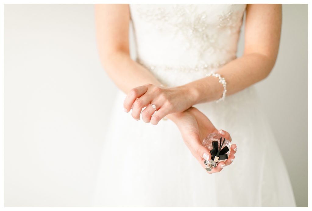 Bride putting on perfume on her wedding day.